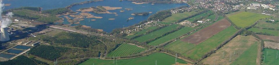 Das Bild zeigt eine Luftansicht der Peitzer Teiche. Rechts davon ist eine Siedlung zu sehen und im Vordergrund mehrere Äcker.
